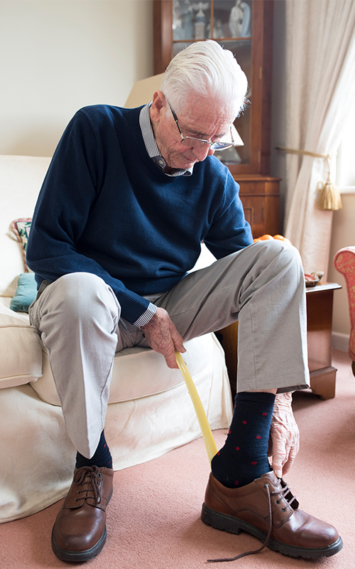 Ein Mann nutzt Anziehhilfen für Senioren