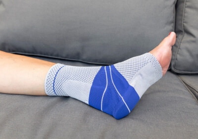 Fuß mit Achillessehnenbandage auf einer grauen Couch