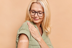 Eine Frau trägt ein medizinisches Pflaster auf ihrem Oberarm